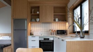 Una cocina compacta con armarios de madera, horno empotrado y microondas.