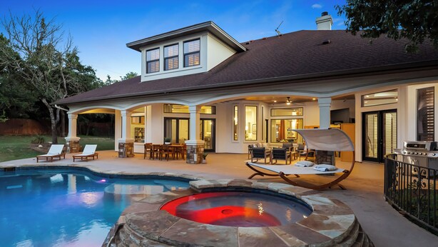 A house with a swimming pool, hot tub, and outdoor seating area.