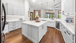 A spacious kitchen with white cabinetry, a large island, and wooden flooring.