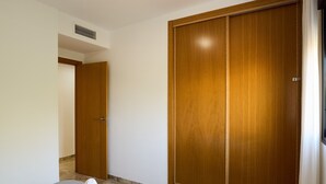 Una habitación de hotel con una cama, un armario de madera y la puerta del baño.