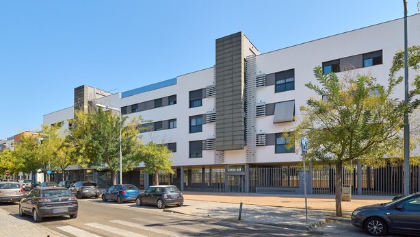 Un edificio moderno de varios pisos, un estacionamiento y una calle con automóviles.