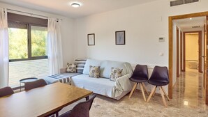 Una sala de estar moderna con un sofá, sillas, una mesa de comedor y un ventanal con cortinas.
