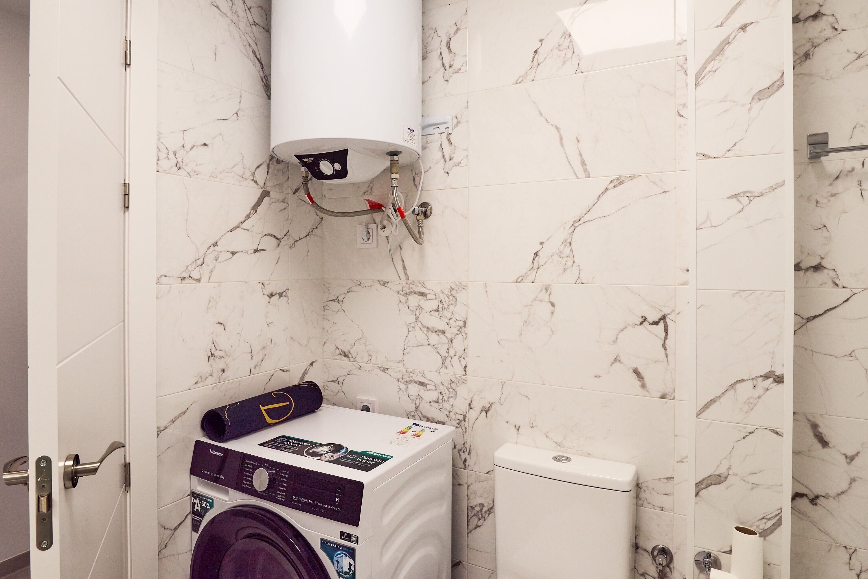 A bathroom with a washing machine, toilet, and a water heater.