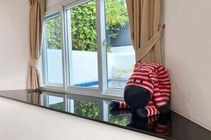 A room with a window, curtains, and a plush toy leaning against the window sill. - Chalong Hideaway Pool Villa (Phuket)