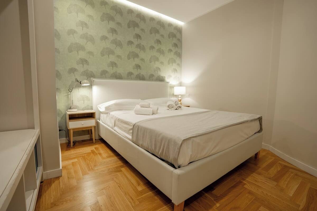 A neatly arranged bedroom with a bed, bedside tables, and a lamp.