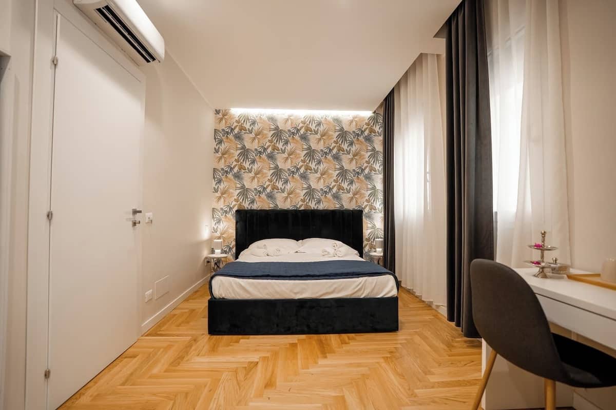 A bedroom with a bed, a desk, and a chair.