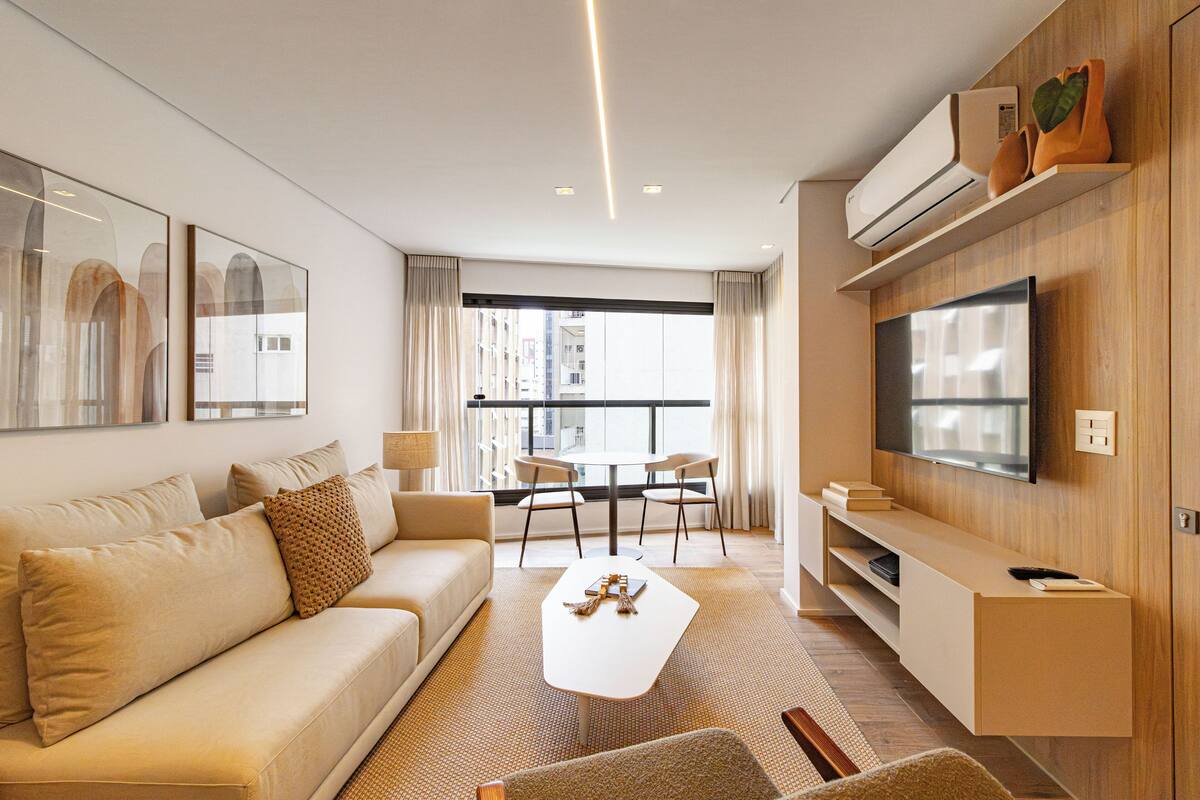 Una sala de estar moderna con un sofá, una mesa de centro y un televisor. Hay un comedor con sillas y una mesa.