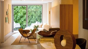 Ein modernes Wohnzimmer mit einer Couch, zwei Sesseln, einem Couchtisch und einem Bücherregal.