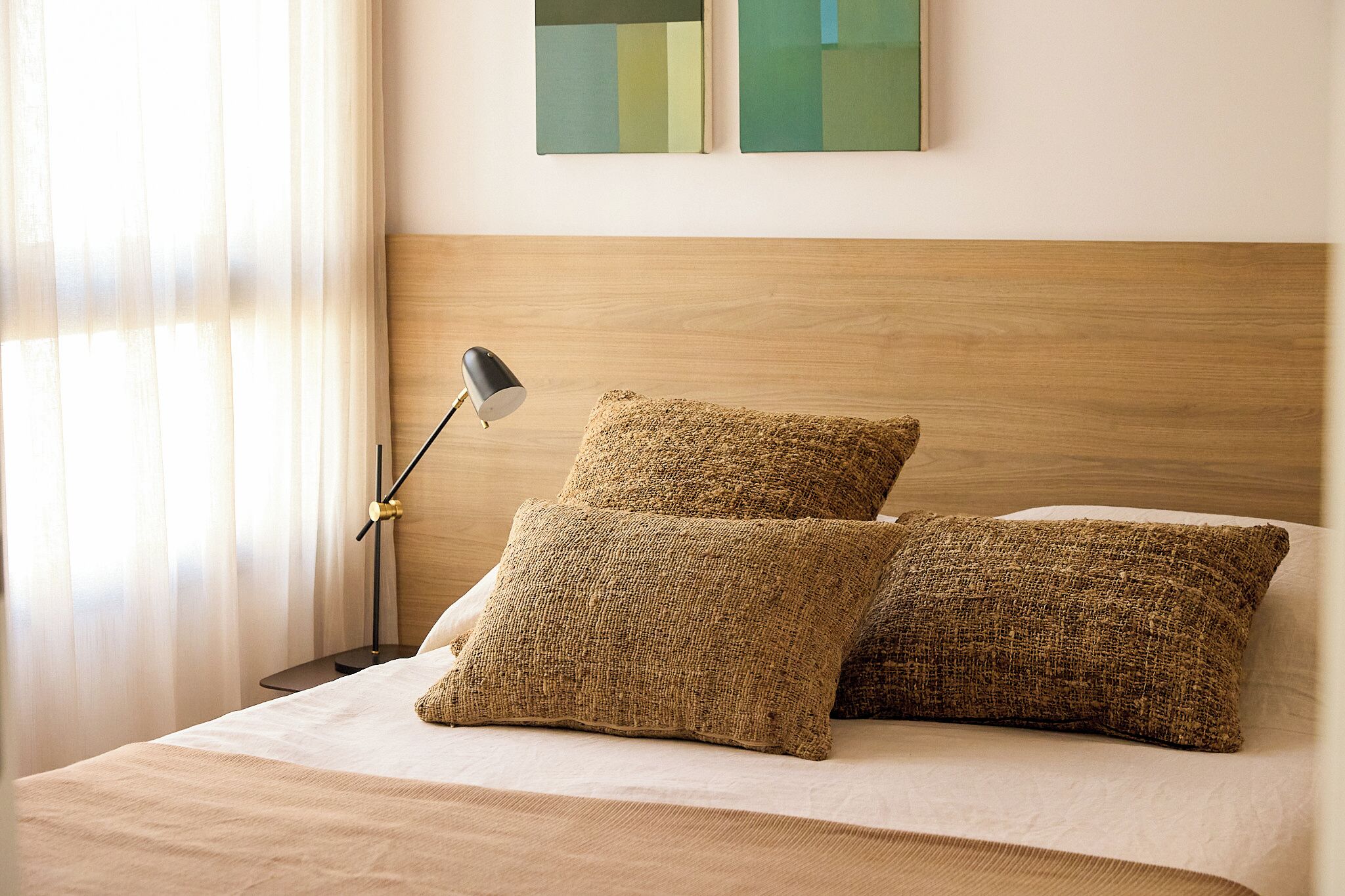 Un letto rifatto con due cuscini decorativi e una lampada da comodino.