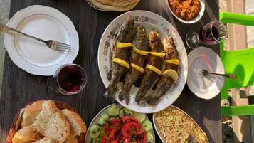 Una mesa servida con diversos platos, incluyendo pescado, pan, ensalada y un bol de pasta.