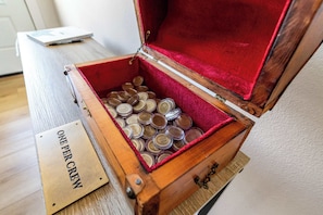 Une caisse en bois, dont l’intérieur est rouge, remplie de récipients métalliques, et portant une étiquette indiquant : « UN SEULEMENT PAR ÉQUIPAGE ».