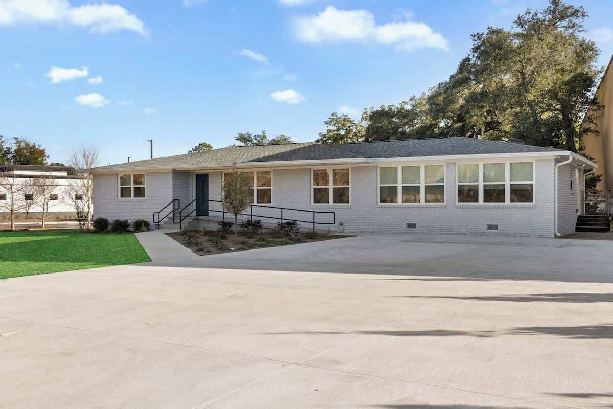 A single-story building with a flat roof, large windows, and a concrete driveway.