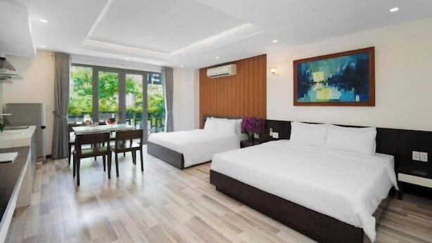 Une chambre d’hôtel avec deux lits, un coin repas et une grande fenêtre.