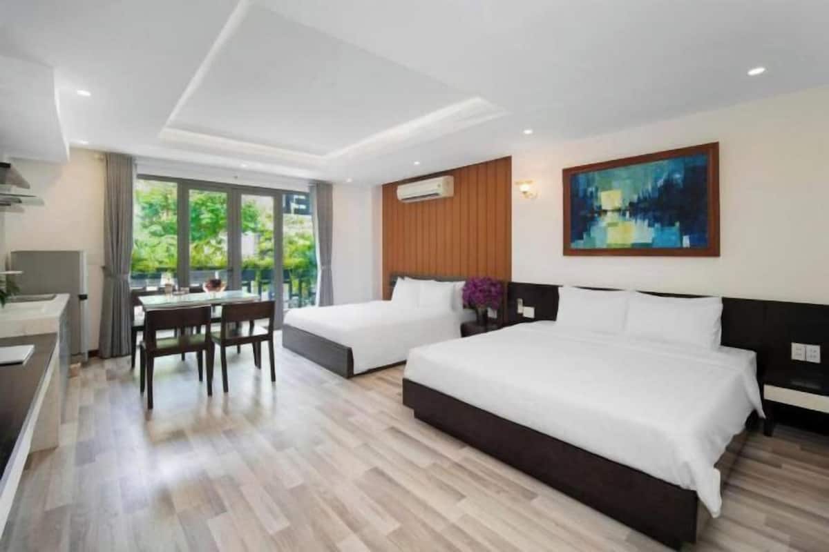 A hotel room with two beds, a dining area, and a large window.