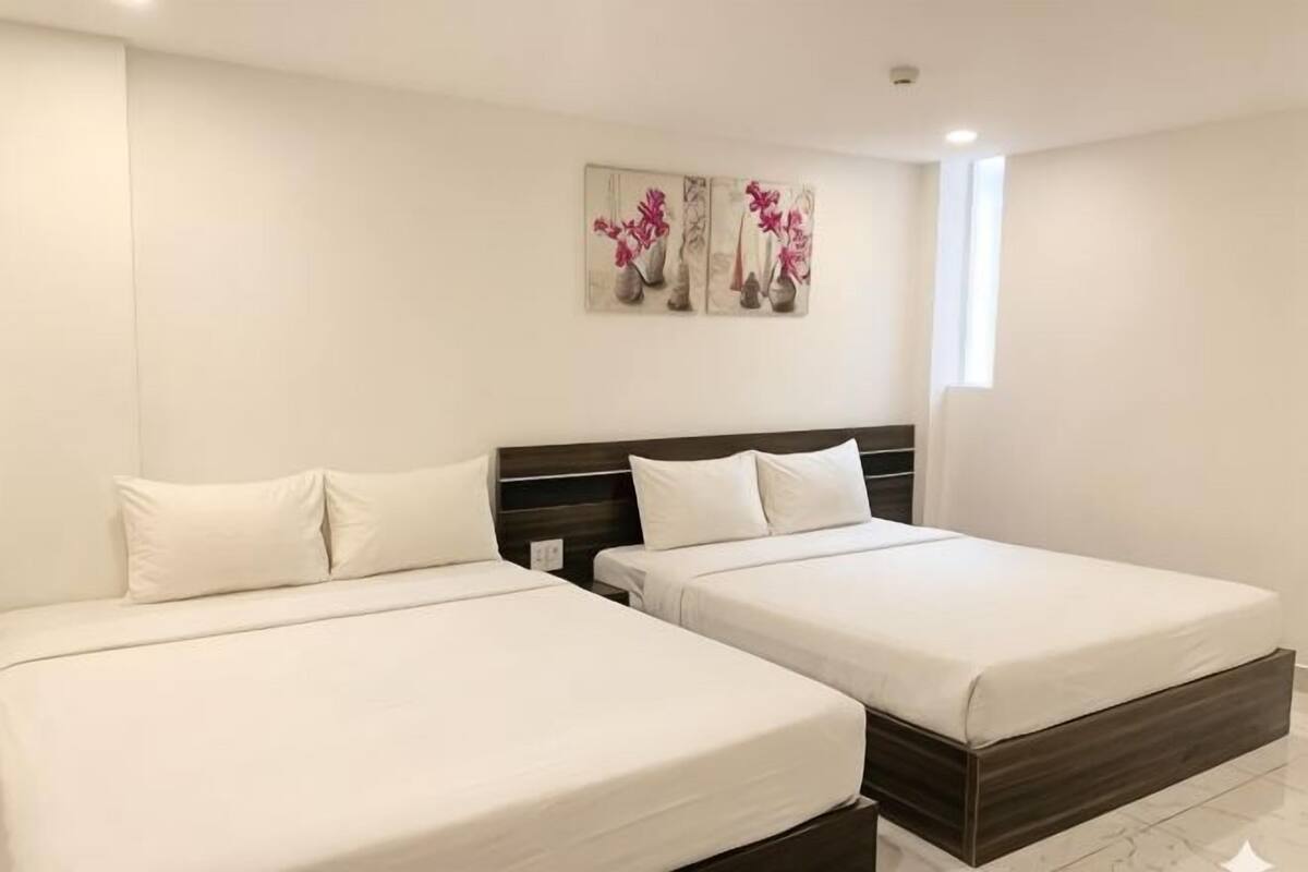 A hotel room with two beds, a nightstand, a wall-mounted artwork, and a window.