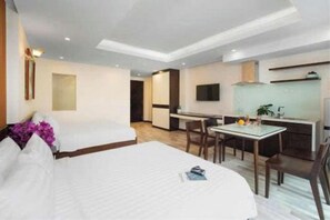 A hotel room with a bed, a desk, and a kitchenette.