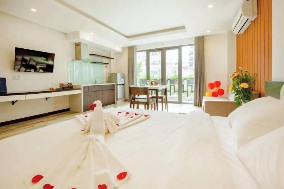 A hotel room with a bed, a dining area, and a kitchen.