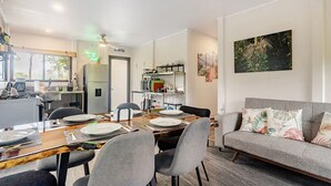 Ein modernes Wohnzimmer mit Essbereich, grauem Sofa und einer Küche im Hintergrund.