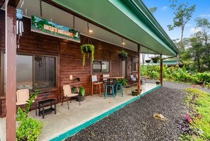 Een houten chalet met een overdekte veranda, buitenmeubels en hangplanten.