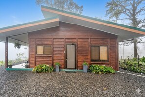 Een modern houten huis met een overdekte veranda, een voordeur en twee ramen.