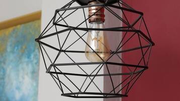 Una lámpara metálica de diseño geométrico con una bombilla de filamento visible.