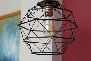 Una lámpara metálica de diseño geométrico con una bombilla de filamento visible.