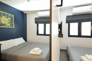 Ein Hotelzimmer mit zwei Betten, einem Bild an der Wand und einer Klimaanlage.