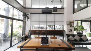 A modern interior with a wooden dining table, black chairs, and a black sofa with cushions. - Wire Bangkok Prakhanong (Bangkok)