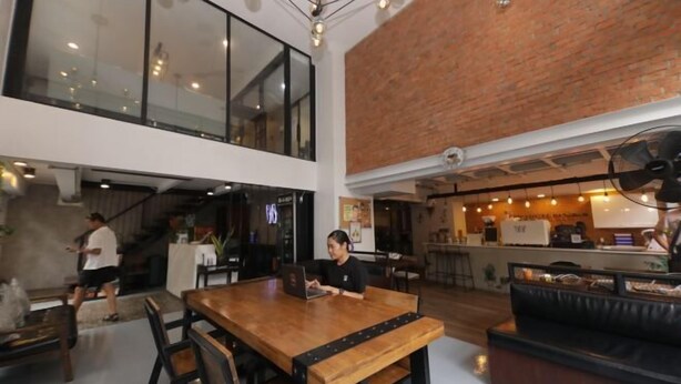 A modern interior with a wooden dining table, black chairs, and a brick wall. - Wire Bangkok Prakhanong (Bangkok)