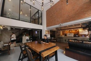Um interior moderno com uma mesa de jantar de madeira, cadeiras pretas e uma parede de tijolos.