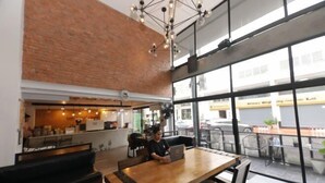 A modern cafe with a brick wall, large windows, and a wooden table with a laptop. - Wire Bangkok Prakhanong (Bangkok)