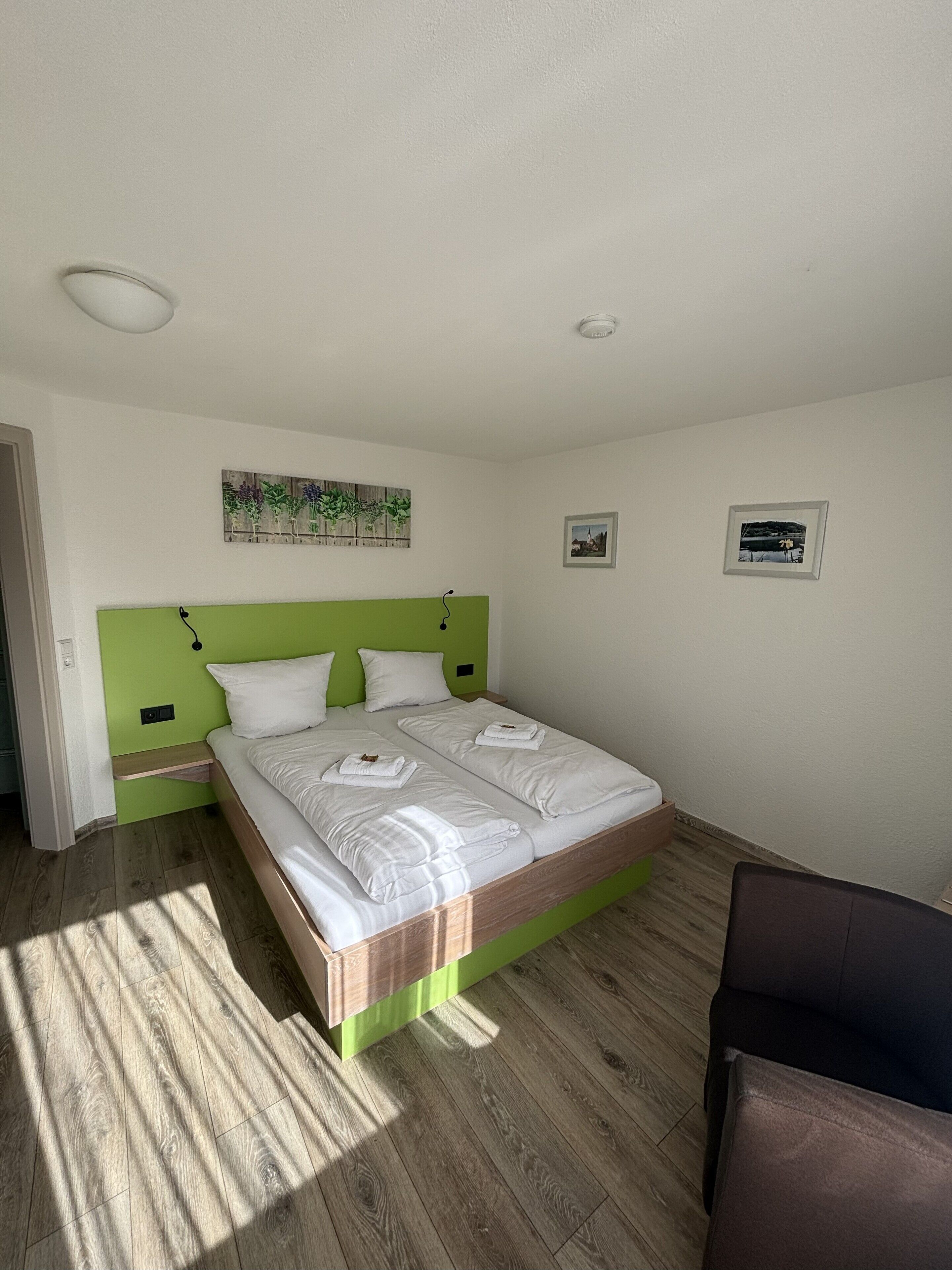 A neatly arranged bedroom with a single bed, a green headboard, and two bedside tables.