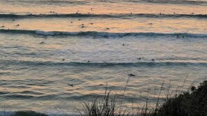 A sunset over the ocean with waves and a clear horizon.