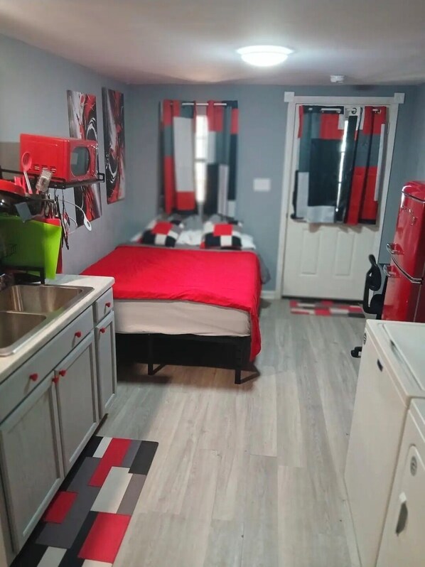 Quarto compacto com cama, cozinha compacta e banheiro.