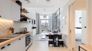 A modern kitchen with a central island, built-in appliances, and a dining area with a view of the city. - Dubai Hills Sleeps 4 With Awesome Swimming Pool (Dubai)
