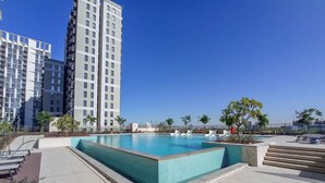 A rooftop swimming pool with clear blue water, surrounded by modern buildings and some greenery. - Dubai Hills Sleeps 4 With Awesome Swimming Pool (Dubai)