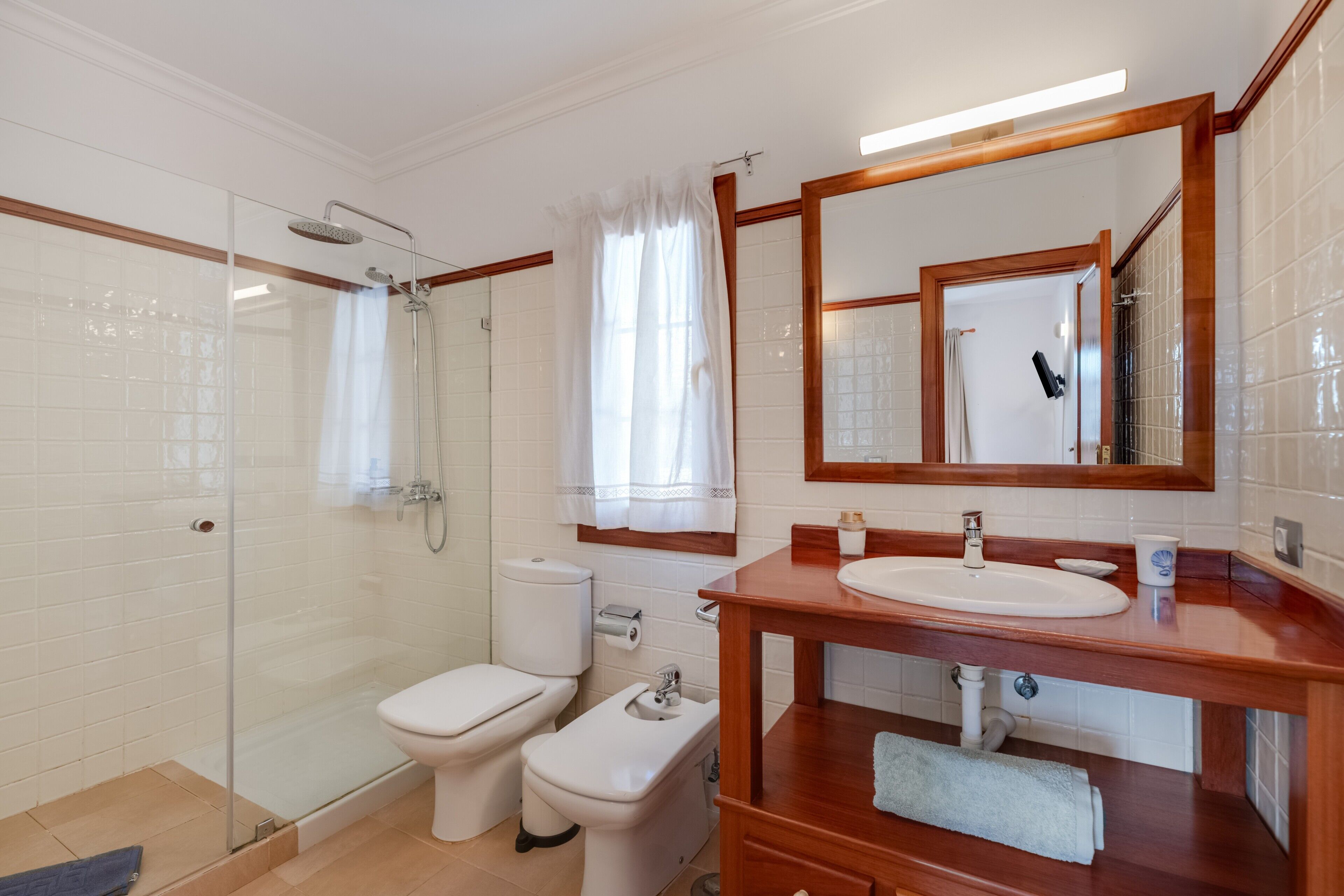Une salle de bain avec une douche à parois de verre, des toilettes, un lavabo avec un miroir et un porte-serviettes.