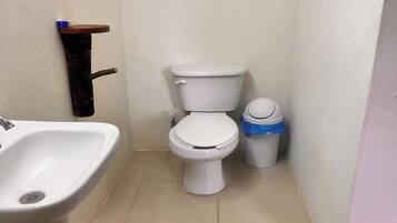 A small bathroom with a toilet, a sink, and a trash bin.