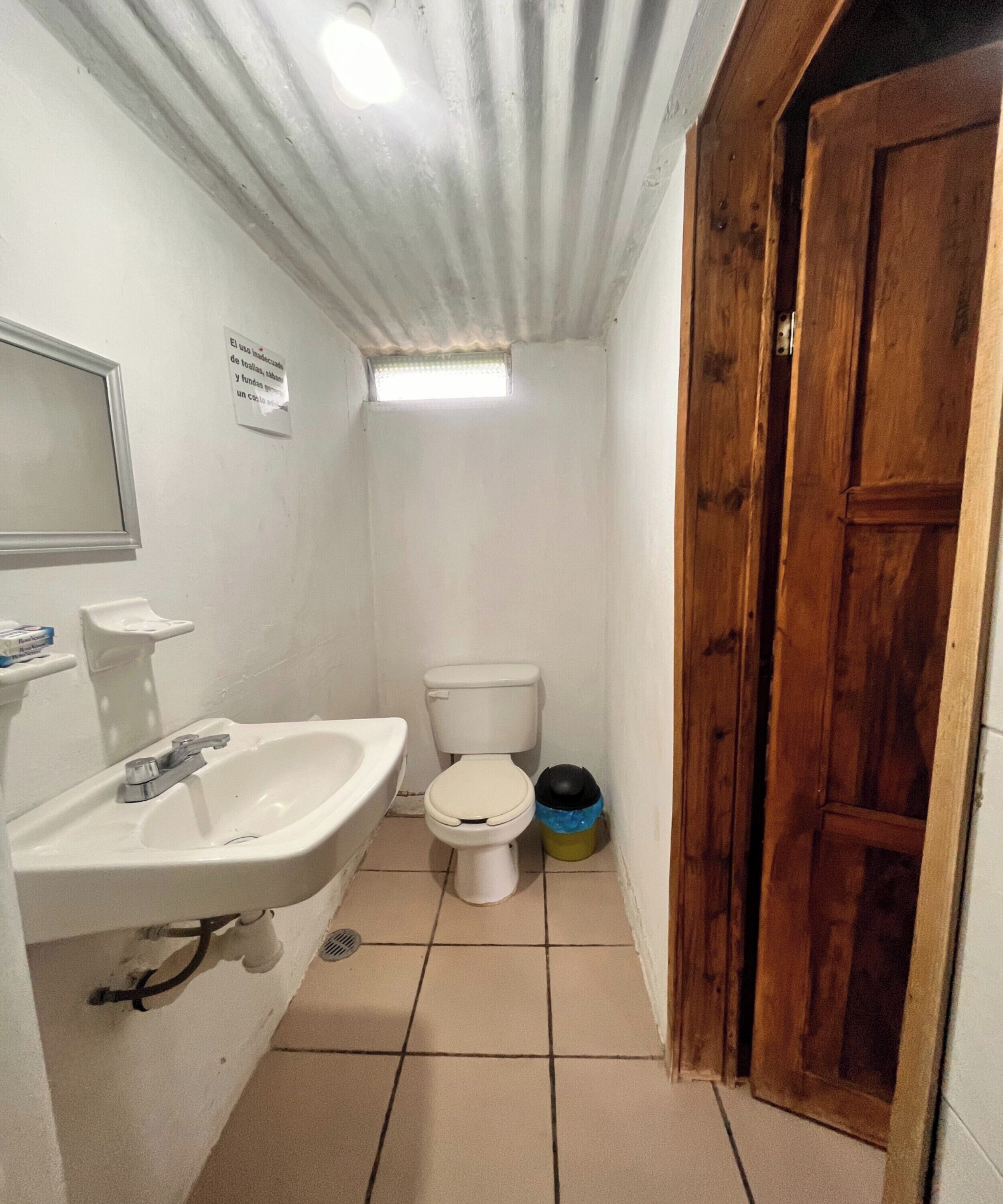 Une petite salle de bain avec un lavabo, des toilettes et une porte en bois.
