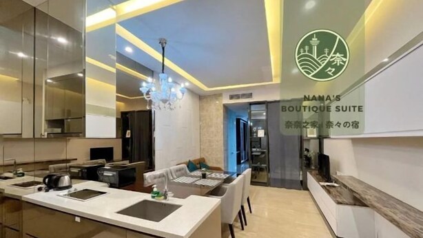 A modern kitchen with a central island, a dining area with a table and chairs, and a visible logo for 'NAMA'S BOUTIQUE SUITE'. - Dorsett Residence KL by Nana's Boutique Suite (Kuala Lumpur)
