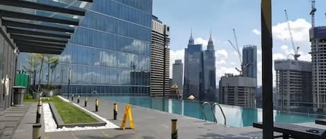 Un área de piscina en la azotea con vistas al horizonte de la ciudad, que incluye edificios modernos y un cielo despejado.
