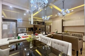 A modern kitchen with a dining area, stainless steel appliances, and a chandelier. - Dorsett Residence KL by Nana's Boutique Suite (Kuala Lumpur)