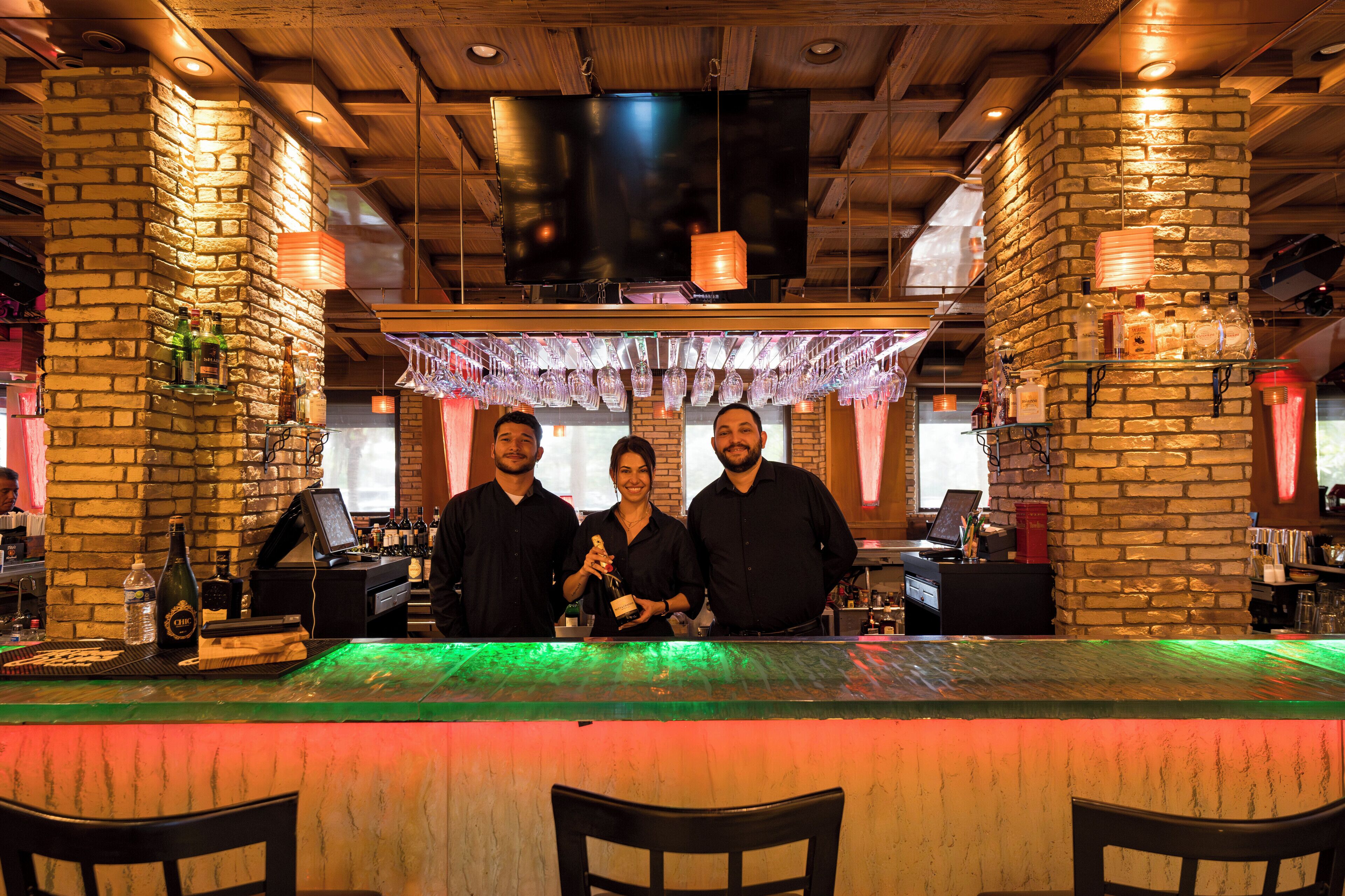 Eine Bar mit Backsteinwand, Holzboden und einer beleuchteten Bar.