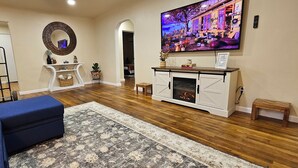 A living room with a blue sofa, a patterned rug, a fireplace, and a TV displaying a scenic view.
