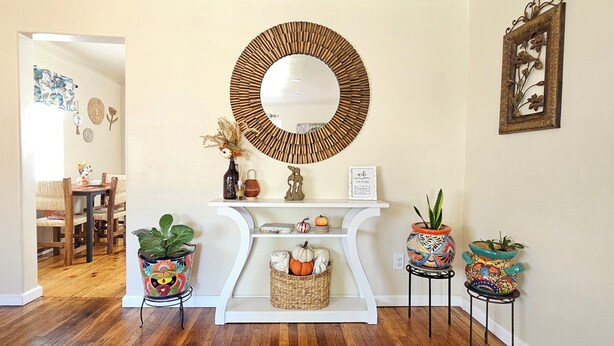 A hallway with a white console table, a mirror, decorative wall art, and potted plants.