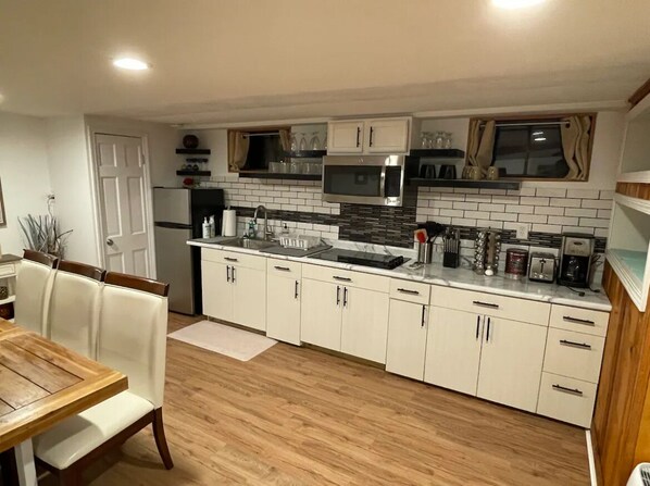 A compact kitchen with white cabinets, a microwave, and a sink. - private 3 bedroom garden apartment in Lincoln square Chicago (Chicago)