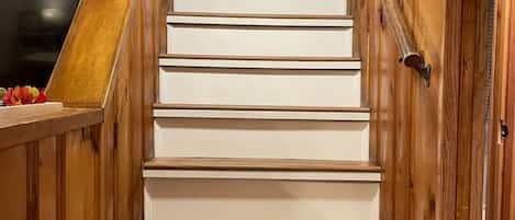 Una escalera de madera con escalones blancos que lleva a una puerta.