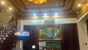 A room with a wooden ceiling, a television mounted on the wall, and a painting above a window. - HOANG HA VILLA (Bac Ninh)