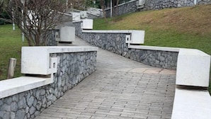 A pathway with stone walls and a brick surface, leading up a grassy slope. - HOANG HA VILLA (Bac Ninh)