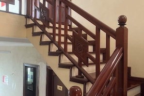 A wooden staircase with a handrail and a decorative balustrade. - HOANG HA VILLA (Bac Ninh)